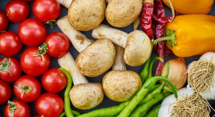 A vibrant assortment of fresh vegetables and mushrooms arranged in a flat lay.