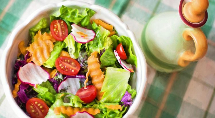 Colorful fresh vegetable salad with cherry tomatoes in a white bowl.